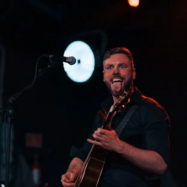 Stephen Cooper performing live on stage with a guitar during an energetic music performance.